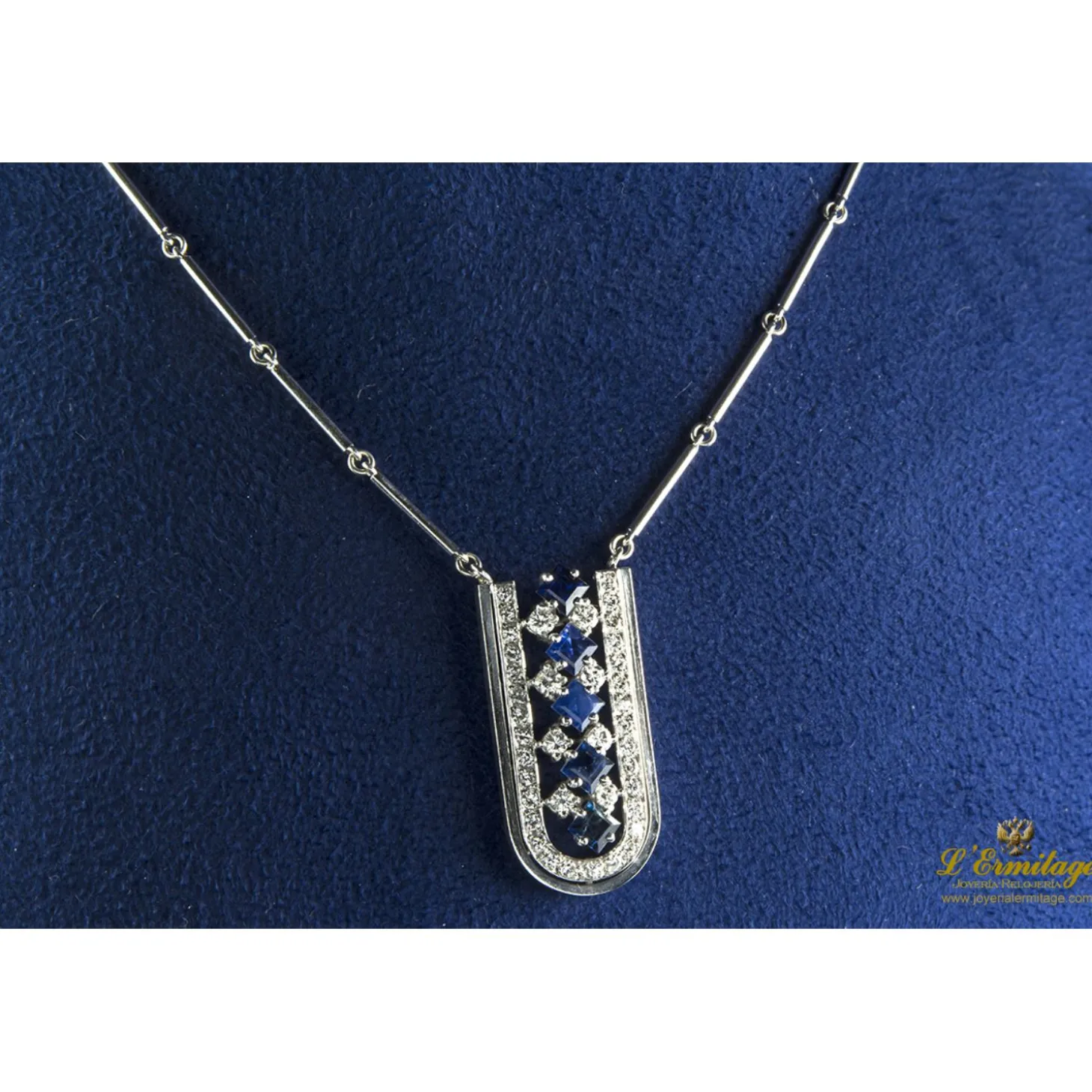 COLLARES Collar de barras cilíndricas realizado en oro blanco. Presenta colgante con zafiros y brillantes.
