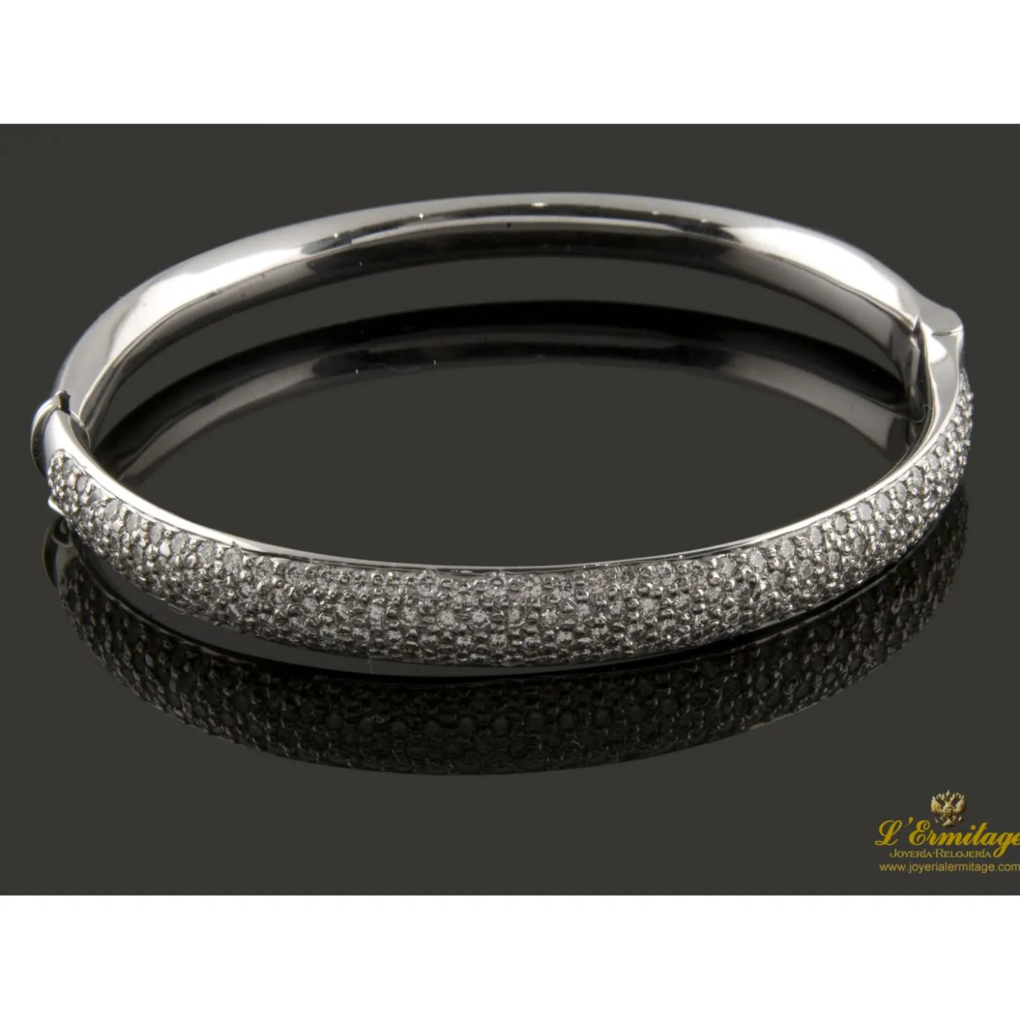 PULSERAS Pulsera rígida de media caña con centro pabe de brillantes montados en oro blanco.
