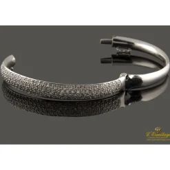 PULSERAS Pulsera rígida de media caña con centro pabe de brillantes montados en oro blanco.